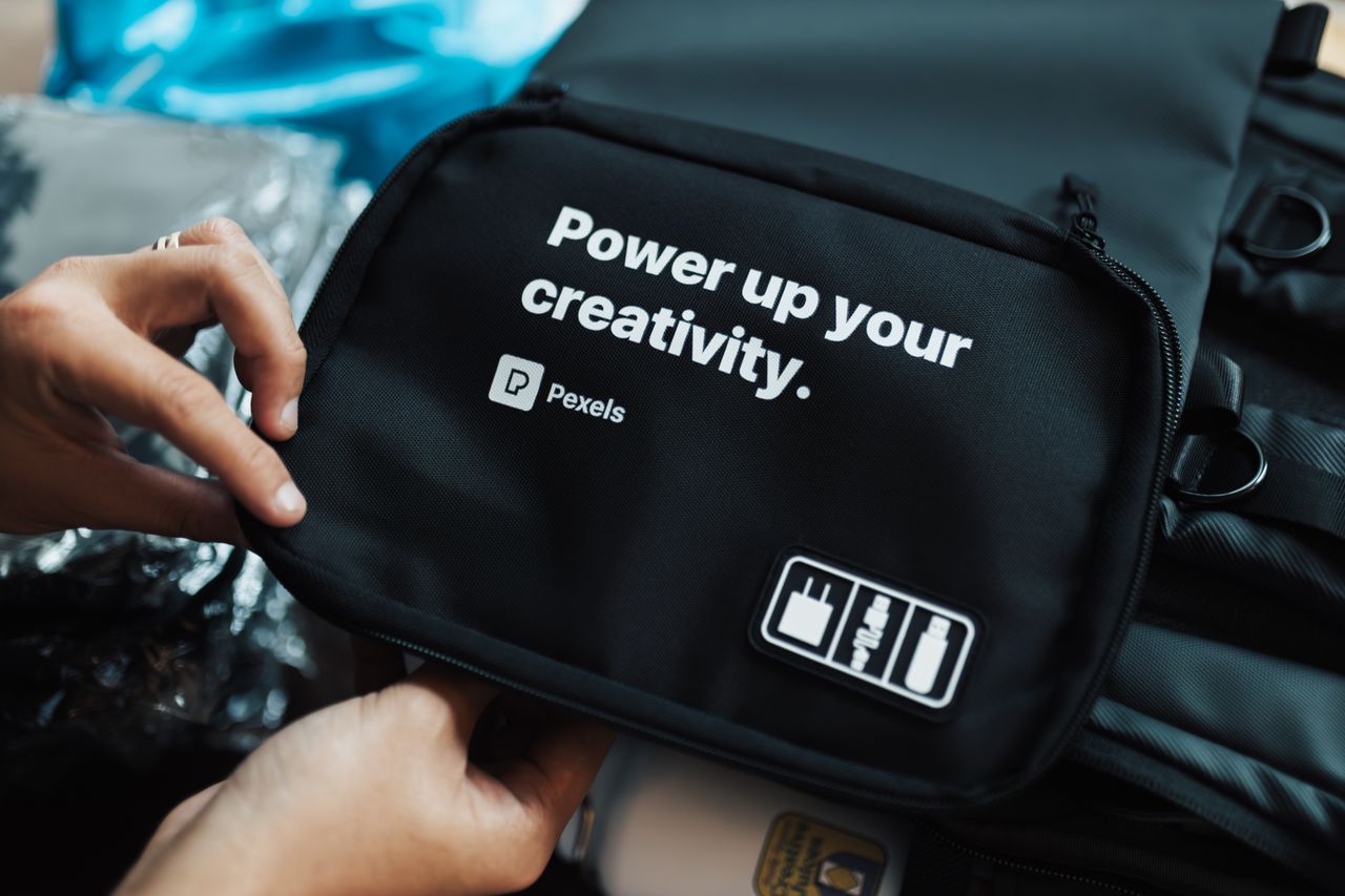 Hands holding a black bag with a creative slogan printed on it.